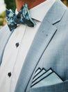blaue blumenfliege mit einstecktuch auf weißes hemd und blauer anzug