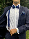 dunkelblaue hosenträger fliege einstecktuch und manschettenknöpfe auf weißes hemd und blauer anzug echtleder